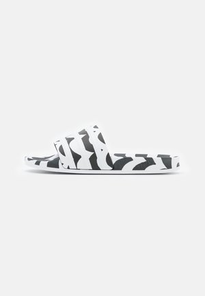 Zwart-witte slippers met patroon, brede band en platte zool, zijaanzicht op een witte achtergrond.