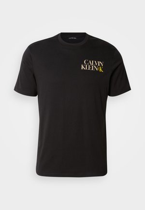 Svart bomull T-skjorte med korte ermer, med et trykk i gull og hvitt på venstre bryst med teksten "CALVIN KLEIN CK." Klassisk rund hals.