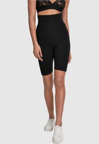 Höga svarta cykelshorts gjorda av stretchigt material, med en elegant design som når till mitten av låret och har en mjuk textur.