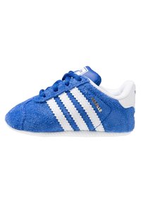 Modrá semišová teniska Adidas Gazelle s bílými pruhy, bílou patní páskou a modrými tkaničkami, pohled ze strany.