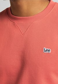 Koraalkleurige sweatshirt van een katoenmix, met een geribbelde ronde hals en een klein geborduurd 'Lee' logo op de borst.