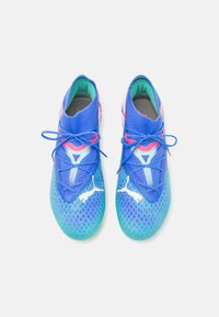 Scarpe da atletica blu e verdi con una tomaia in maglia, caratterizzate da accenti rosa e loghi bianchi. Presentano un design simile a un calzino e una texture a motivi.