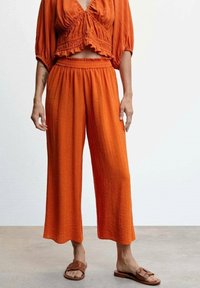 Oranžový dvoudílný outfit sCrop topem z texturované látky a elastickým pasem, spárovaný s volnými širokými kalhotami.