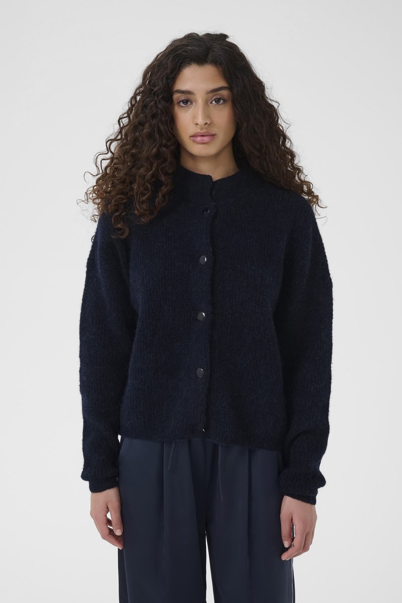 Strikket marineblå cardigan med rund hals, syv svarte knappelukkinger og ribbestrikkede mansjetter. Strukturert, mykt stoff med en avslappet passform.