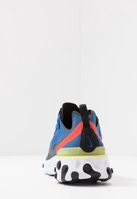 Blå kanvas-sneakers med svarta detaljer, röda och gröna inslag, texturerad sula och dragflik vid hälen. Har Nike-logotyp.