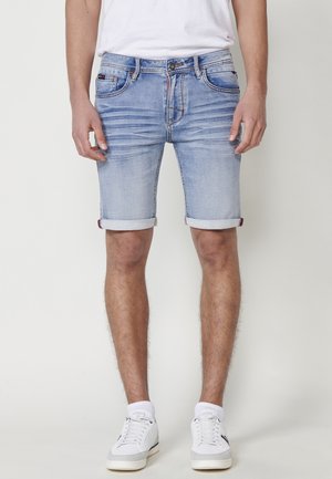 Shorts de denim azul claro con dobladillos enrollados. Presenta cinco bolsillos, un ligero desvanecimiento y acentos de costura en contraste. Ajuste estándar con cremallera.