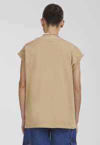 Beige, volné tričko s krátkými rukávy s ohrnutím, kulatým výstřihem a rovním lemem, vyrobené z měkké bavlny.