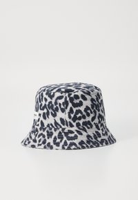 Pălărie tip bucket dintr-un material moale, cu un model leopar alb-negru, având o margine cusută și o etichetă mică pe lateral.