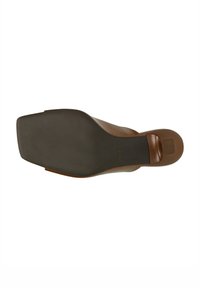 Sandale brune à semelle plate. Tige en cuir lisse avec une semelle extérieure en caoutchouc noir texturé. Design à bout carré et détail de marque subtil.