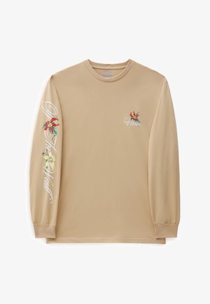 Beigen värinen pitkähihainen paita, jossa punakeltaisia kukkakuvioita, "Vans"-logo rinnassa ja vasemman hihan valkoiset käsinkirjoitetut tekstit.
