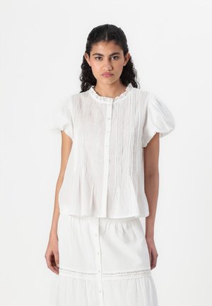 Hvit kortermet bluse med knapper foran, blondekrage, plissédetaljer og flared søm. Stoffet ser lett og teksturert ut.