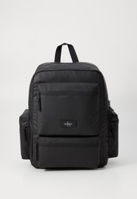 Black nylon backpack with multiple zippered pockets, padded straps, and a top handle. Features a logo patch on the front. Simple design.
