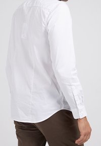 Witte button-up blouse van katoen, met lange mouwen en een afgeronde zoom. Heeft knoopmanchetten en een etiket dat zichtbaar is op de achterkant.