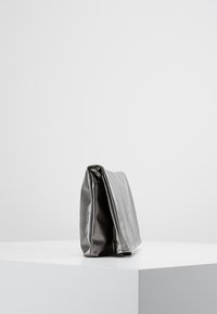 Metallinhohtoinen harmaa nahkalaukku, suorakaiteen muotoinen, sileä pintakuvio, taitetut reunat ja minimalistinen muotoilu ilman näkyviä metalliosia.