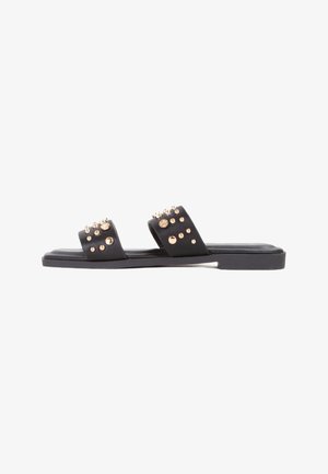 Zwarte platte sandalen met twee brede banden, versierd met gouden en doorzichtige studs, met een eenvoudig ontwerp en een gladde textuur.