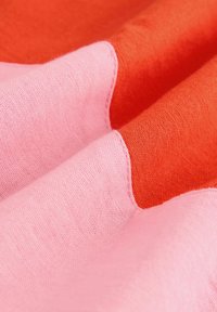 Baumwollstoff mit einem welligen Design und Abschnitten in lebhaftem Pink und Orange. Die Textur ist weich und leicht matt.