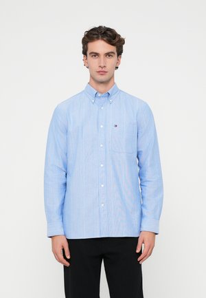 Lichtblauwe overhemden met verticale witte strepen, enkele borstzak en button-down kraag, gemaakt van een gladde stof.