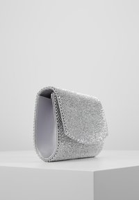 Borsa a pochette argentata rivestita di strass, con patta a ribalta e fodera interna liscia. Forma rettangolare con angoli arrotondati.