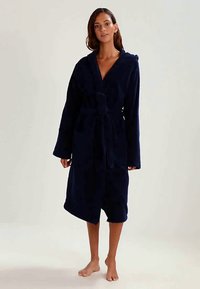Navy blue fleece bathrobe with a hood, long sleeves, belted waist, and two front pockets; soft texture, knee-length design.