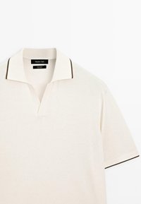Polo a maniche corte in cotone color crema chiaro, con colletto bordato in marrone e design a V, dalla texture morbida e vestibilità rilassata.