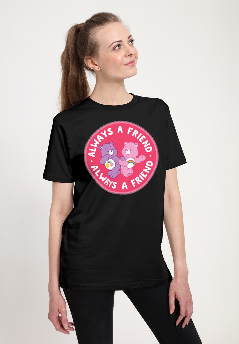 Camiseta negra con un gráfico circular que presenta dos osos de dibujos animados y el texto "Siempre un Amigo" en rosa y blanco.