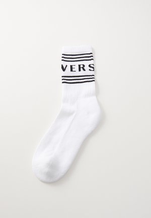 White cotton sock with ribbed top featuring black stripes and the word "VERS" in capital letters across the band. Smooth texture.