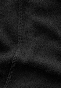 Schwarzer Stoff mit einer glatten Textur, der ein dezentes Strickmuster aufweist. An den Nähten sind sichtbare Nähdetails zu erkennen.
