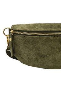 Sac banane en daim vert olive avec une texture lisse, fermeture éclair dorée et quincaillerie accentuée. Il dispose d'une bandoulière détachable pour un port polyvalent.