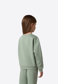 Green cotton sweatshirt with ribbed cuffs and hem, featuring a relaxed fit. The back view shows a smooth texture and simple design.
