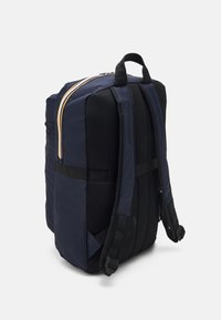 Navy backpack made of durable nylon with mesh accents, featuring a top handle, adjustable straps, and contrasting zipper trim.