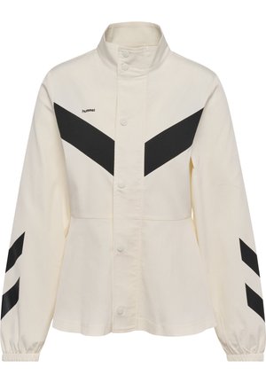 Veste écrue avec col montant, motifs chevrons noirs sur la poitrine et les manches, boutons-pression sur le devant, poignets élastiques et logo "hummel" sur la poitrine gauche.