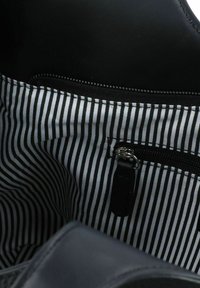 Sac à main en cuir noir avec un intérieur en tissu rayé, comprenant une poche zippée et des fermetures éclair noires.