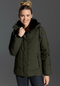 Maslinasto zelena puffer jakna s kapuljačom obloženom krznom, džepovima na zatvarač i kviltanim uzorkom. Ima podesive špage i logotip.