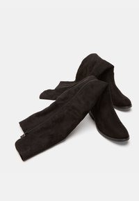 Botines de ante negros con una textura suave, que presentan un cierre de cremallera lateral y un caña ajustada que se afina en la parte superior.