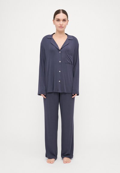 Das navyblaue Schlafanzugset besteht aus einem kurzärmeligen, knöpfbaren Hemd mit Kragen und Tasche sowie einer locker sitzenden Hose, beide mit einer subtilen gerippten Textur.