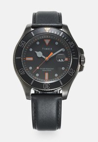 Timex pulkstenis ar melnu metāla rāmi, melnu ciparnīcu, oranžiem akcentiem un ādas siksniņu. Funkcijas ietver datuma logu un 100 m ūdens izturību.