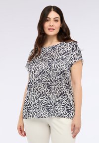 Lyhythihainen paita kevyttä kangasta, jossa on tummansininen ja valkoinen lehtikuvio. Pyöreä kaula-auko ja rento malli, jossa on sileä pinta.