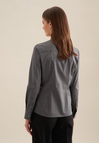 Camicia grigia con bottoni, maniche lunghe, texture liscia e motivo a scacchi sottile, con polsini arrotondati e un design con yoke posteriore.