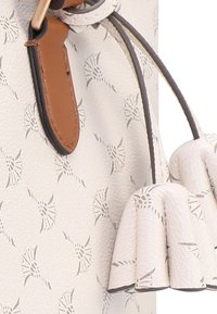 Borsa da donna realizzata in pelle bianca testurizzata, con un delicato motivo a rilievo e dettagli in pelle marrone. Dettaglio con nappina arrotondata.