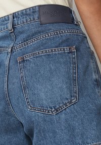 Shorts in denim con una tonalità di blu medio, con tasche posteriori e un'etichetta in pelle Marc O'Polo sulla vita.