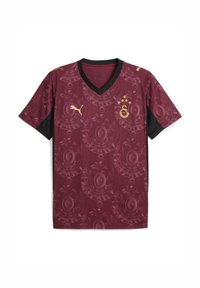 Bordeauxfarbenes Fußballtrikot mit einem schwarzen V-Ausschnitt, das ein kreisförmiges Blumenmuster und goldene Akzente aufweist, darunter ein Logo und Sterne.