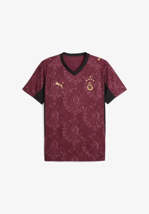 Burgundin värinen jalkapallopaita, jossa on musta V-pääntie, esittelee pyöreää kukkakuviota ja kultaisia yksityiskohtia, mukaan lukien logo ja tähdet.