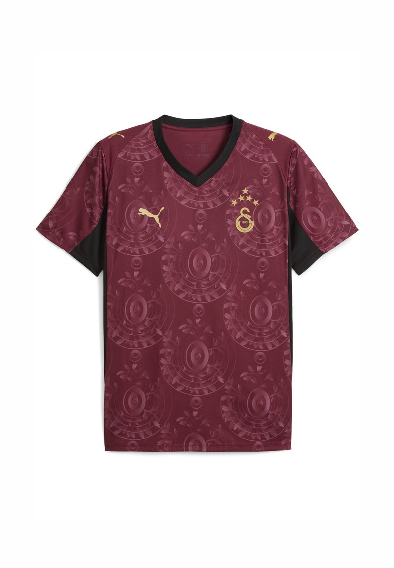 Bordeauxfärgad fotbollströja med svart V-ringning, som har ett runt blommönster och gyllene detaljer, inklusive en logo och stjärnor.