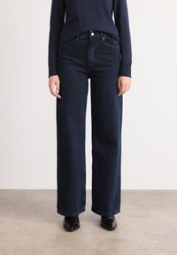Blauwe wijde jeans van denim, met een hoge taille, zijzakken en een eenvoudige knoopsluiting. Glad textuur en gelijkmatige kleur.