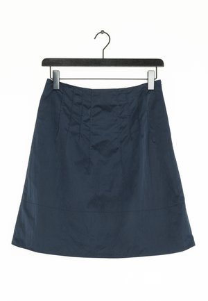 Granatowa spódnica o rozkloszowanym kroju, z zakładkami w talii i gładką fakturą. Zawieszona na czarnym metalowym wieszaku.