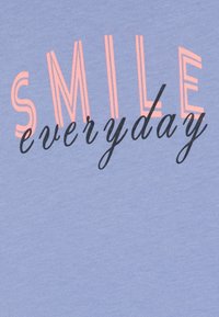 Šviesiai mėlynas medvilninis marškinėliai su ryškiu rožiniu tekstu "SMILE" ir juodai užrašytu kursyvu "everyday", turintys švelnų ir lygų paviršių.