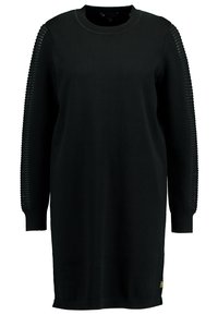 Abito nero lavorato a maglia con scollatura a girocollo e maniche lunghe, dotato di un design testurizzato e a costine sui lati. Tessuto morbido, arrivando fino al ginocchio.