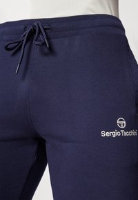 Mornarsko plave hlače za trčanje od mekog materijala s pojasom na vezivanje, s bijelim izvezenim logotipom na bedru.