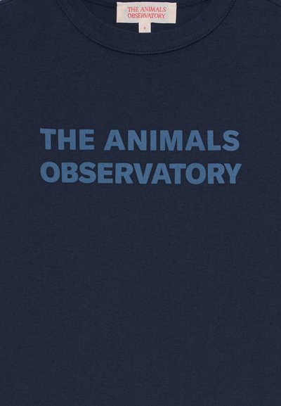 Jūras zilas krāsas krekls ar uzrakstu "THE ANIMALS OBSERVATORY" lieliem zilas krāsas lielajiem burtiem priekšā, etiķete redzama iekšpusē uz apkakles.