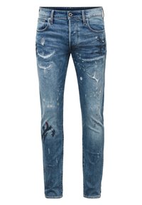 Blå jeans i denim med slitna detaljer, färgstänk och en slim-fit design. Har en traditionell knäppning med knapp och fem fickor.